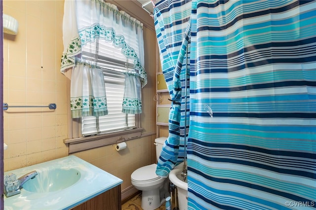 bathroom with toilet, curtained shower, tile walls, and vanity