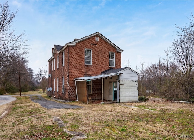 rear view of property with brick siding and aphalt driveway