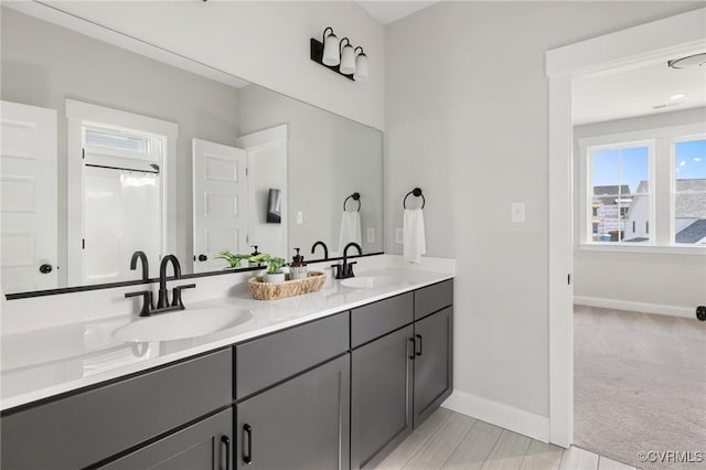 full bath featuring a sink, baseboards, and double vanity