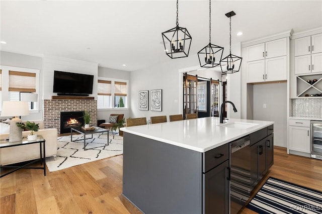 kitchen featuring a sink, light countertops, white cabinets, dishwasher, and light wood-type flooring