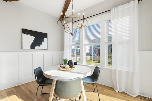 dining space featuring a chandelier, a decorative wall, light wood-style flooring, and beamed ceiling