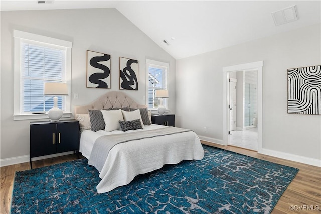 bedroom with visible vents, baseboards, lofted ceiling, and wood finished floors