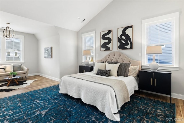 bedroom with lofted ceiling, multiple windows, wood finished floors, and visible vents