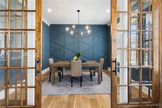 dining area featuring baseboards, an inviting chandelier, wood finished floors, and ornamental molding