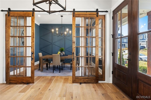 interior space featuring a chandelier, french doors, a barn door, and hardwood / wood-style floors