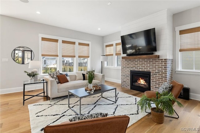 living room featuring a brick fireplace, recessed lighting, wood finished floors, and baseboards