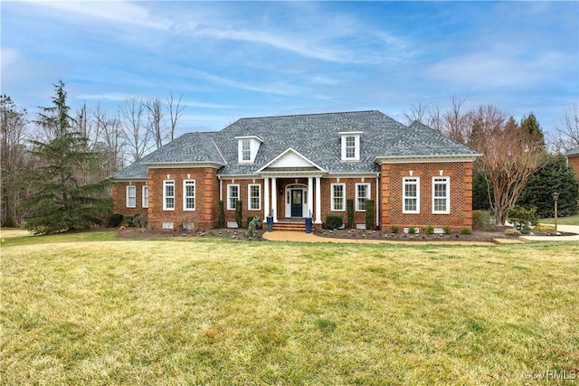 view of front of property with brick siding, a front lawn, and roof with shingles