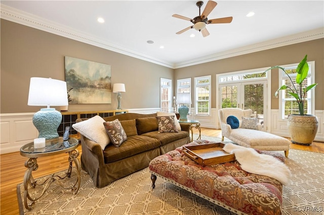 living area featuring light wood-style flooring, recessed lighting, ceiling fan, wainscoting, and crown molding