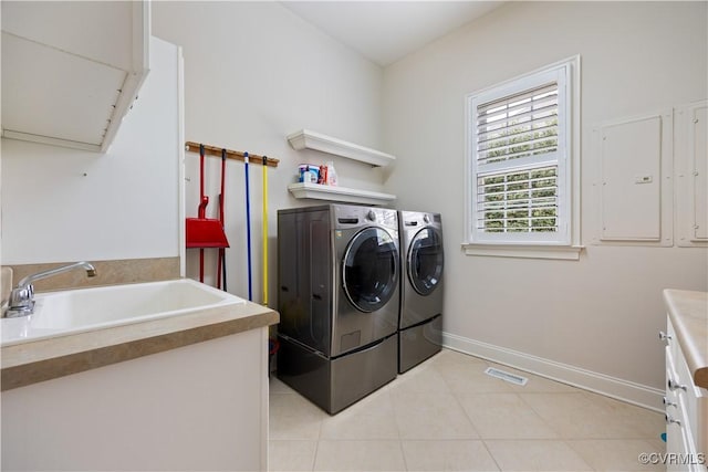 laundry area featuring independent washer and dryer, a sink, cabinet space, light tile patterned flooring, and baseboards