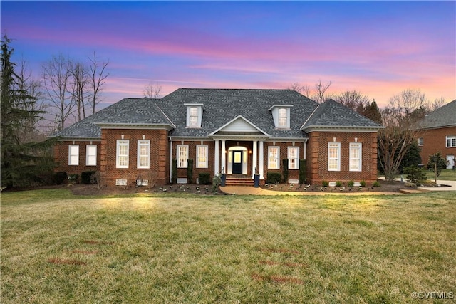 view of front of property with a lawn, brick siding, and roof with shingles