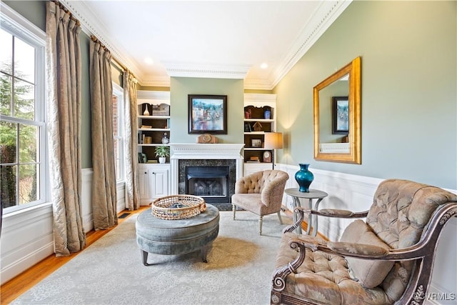 living area with plenty of natural light, wainscoting, and crown molding