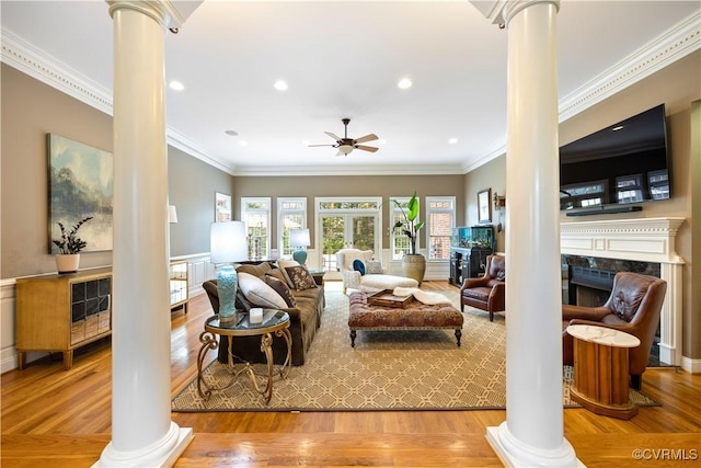 living room with decorative columns, wood finished floors, ceiling fan, and ornamental molding