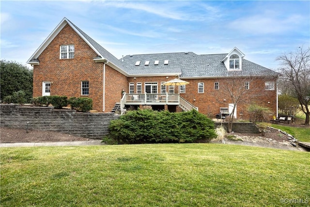 rear view of property with brick siding, a deck, stairs, and a lawn