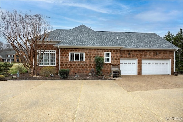 view of side of property featuring concrete driveway, a garage, brick siding, and a shingled roof