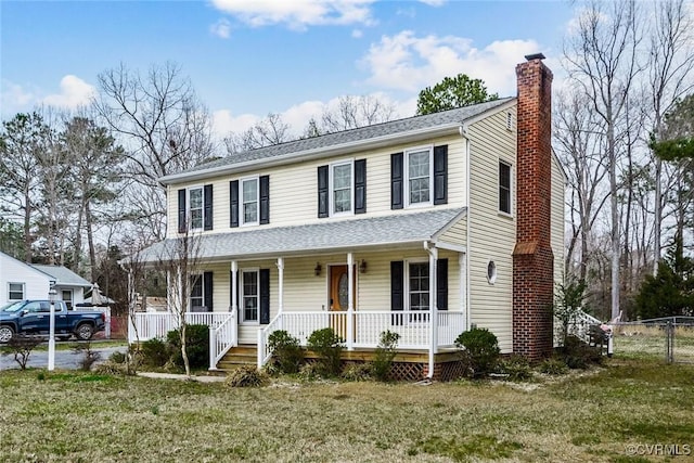 view of front of house with a porch, fence, a front lawn, and a chimney