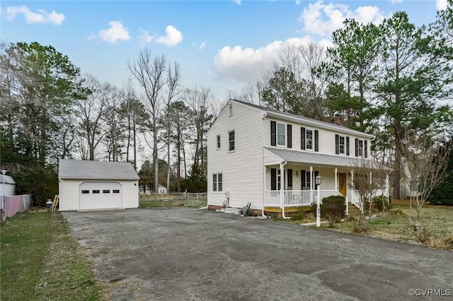 view of front of property featuring an outbuilding, a detached garage, fence, covered porch, and a chimney