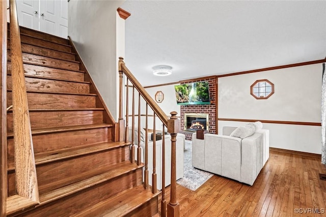 stairs with ornamental molding, a fireplace, baseboards, and hardwood / wood-style floors