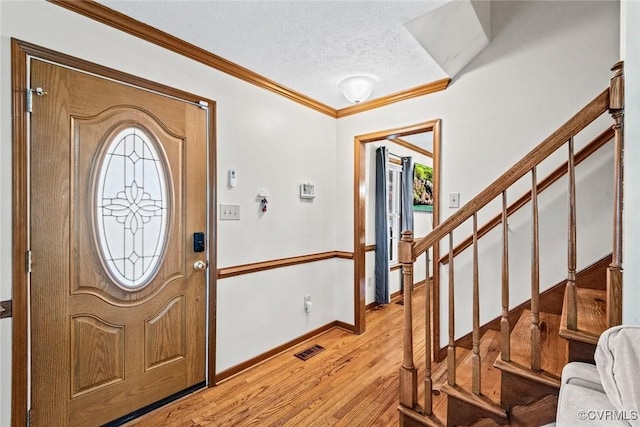 foyer with visible vents, light wood-style flooring, ornamental molding, stairs, and a textured ceiling