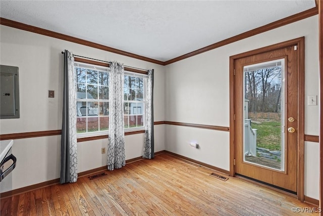 unfurnished room featuring baseboards, visible vents, light wood-style flooring, electric panel, and crown molding