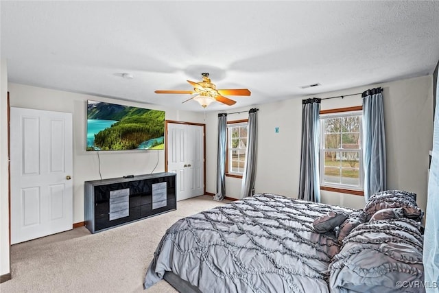 carpeted bedroom featuring a textured ceiling, a ceiling fan, visible vents, and baseboards