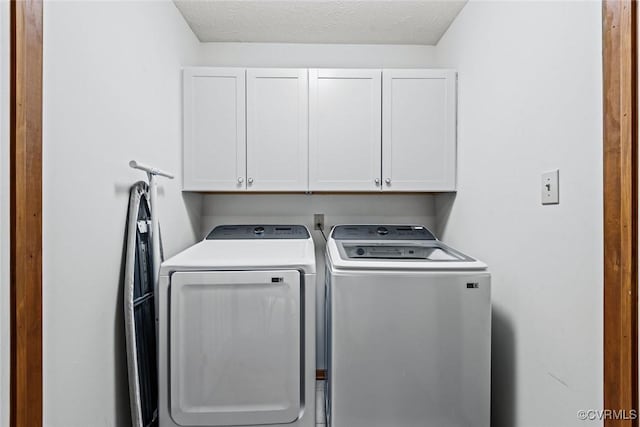 washroom with cabinet space, washer and dryer, and a textured ceiling