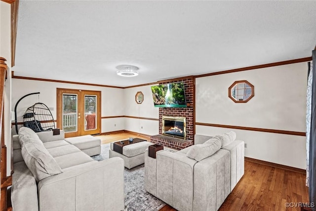 living room featuring ornamental molding, a brick fireplace, french doors, and wood finished floors