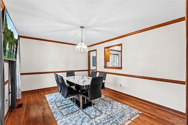 dining room with crown molding, wood finished floors, baseboards, and a chandelier