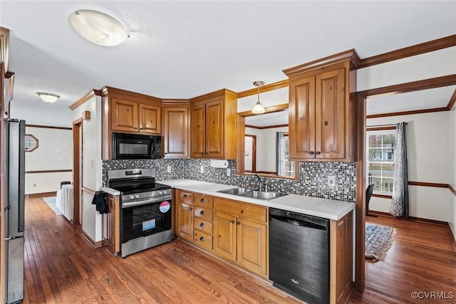 kitchen featuring wood finished floors, black appliances, light countertops, and a sink