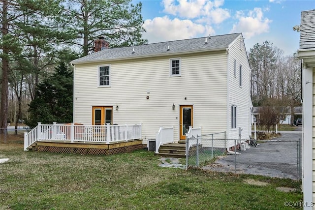 back of property with a lawn, a deck, a chimney, and fence