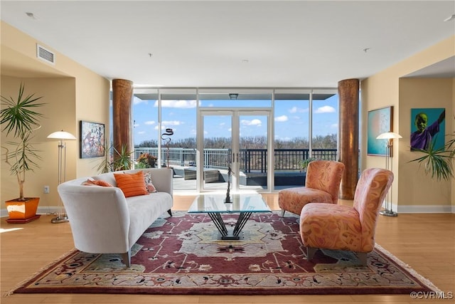 living room featuring visible vents, a wall of windows, baseboards, and wood finished floors