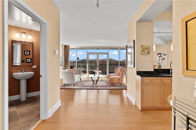 hall with floor to ceiling windows, baseboards, light wood finished floors, and a sink