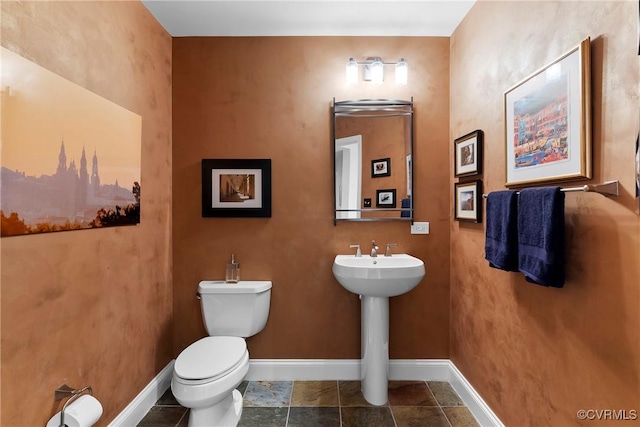 bathroom with a sink, baseboards, and toilet