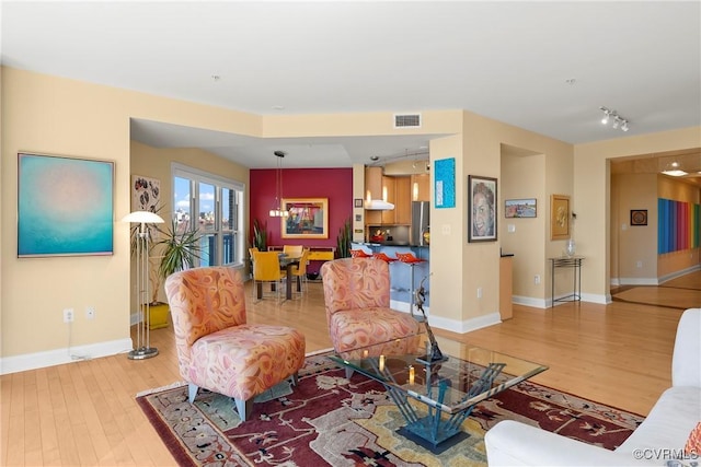 living area with light wood-type flooring, baseboards, and visible vents