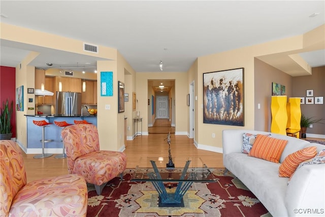 living area with visible vents, light wood-style flooring, and baseboards