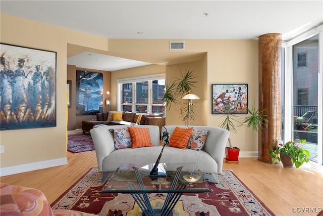 living room featuring visible vents, baseboards, and wood finished floors