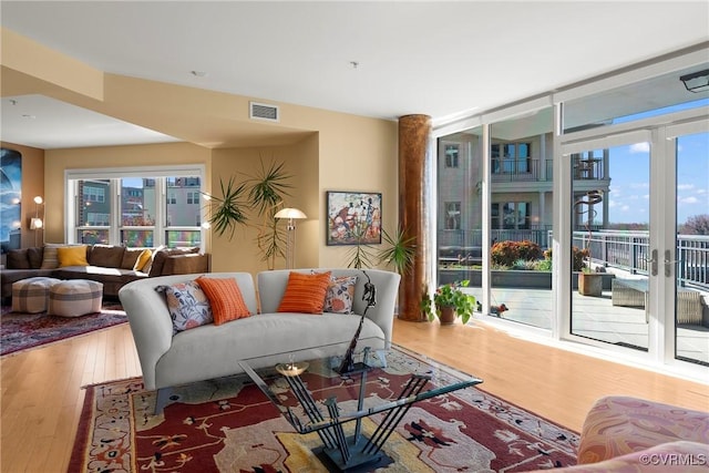 living room with visible vents, wood finished floors, and floor to ceiling windows