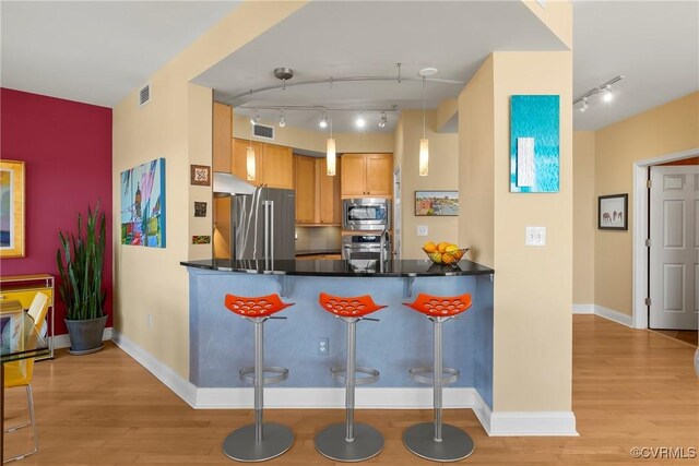 kitchen with visible vents, a peninsula, appliances with stainless steel finishes, and light wood-style flooring