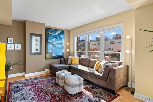 living area featuring a city view, light wood-style flooring, and baseboards