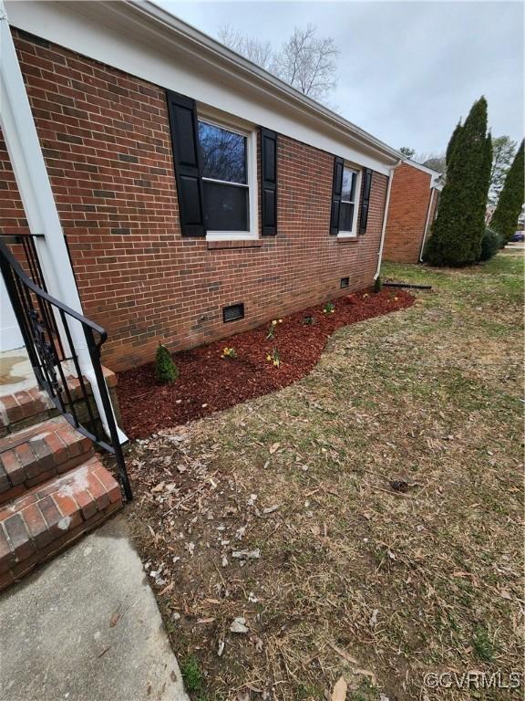 view of side of home with brick siding and crawl space