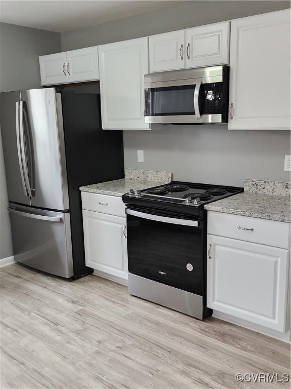 kitchen featuring light stone counters, appliances with stainless steel finishes, white cabinets, and light wood finished floors