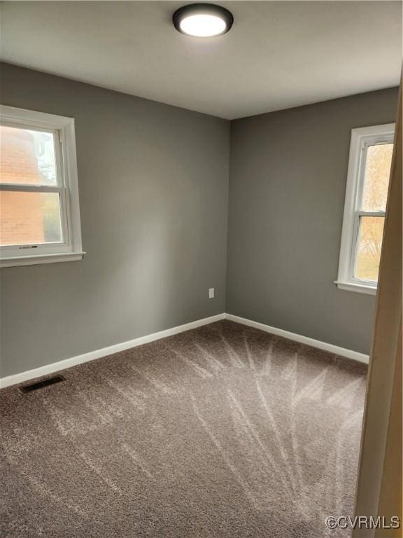 carpeted spare room featuring visible vents and baseboards