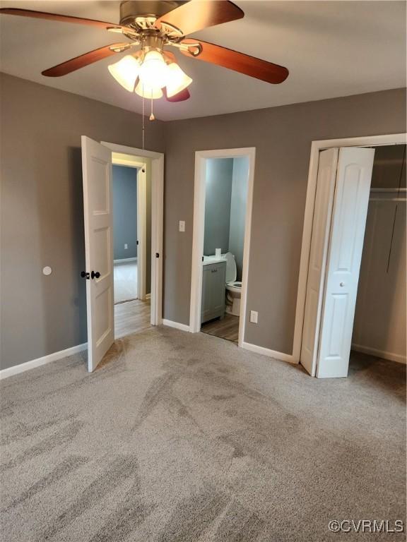 unfurnished bedroom with baseboards, carpet floors, ceiling fan, a closet, and ensuite bathroom