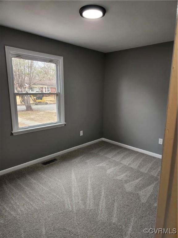 carpeted empty room featuring visible vents and baseboards