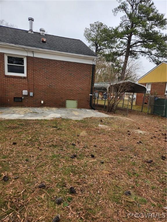 view of yard with a carport, a patio, and fence