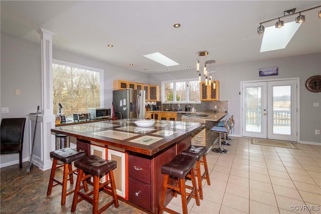 kitchen featuring tasteful backsplash, a breakfast bar area, french doors, a skylight, and stainless steel appliances