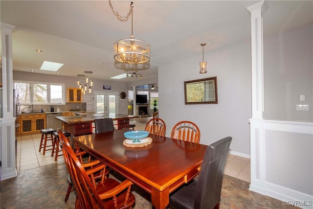 dining area with baseboards, dark tile patterned floors, recessed lighting, a skylight, and an inviting chandelier