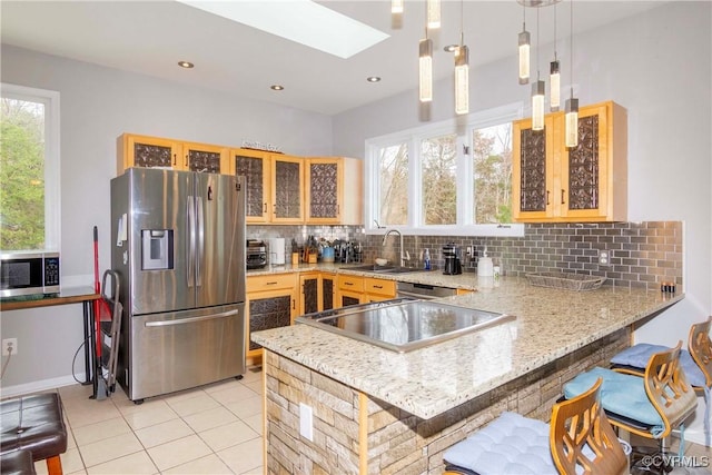 kitchen with a breakfast bar area, a peninsula, a sink, appliances with stainless steel finishes, and tasteful backsplash