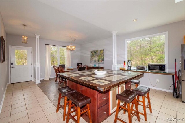 dining space with light tile patterned floors, baseboards, and ornate columns