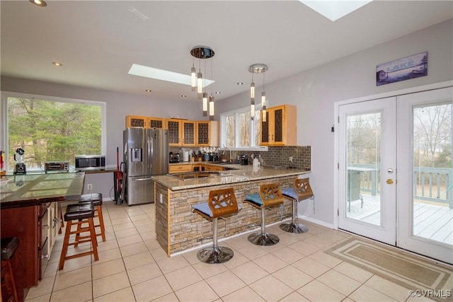 kitchen with light tile patterned floors, appliances with stainless steel finishes, a skylight, and a peninsula