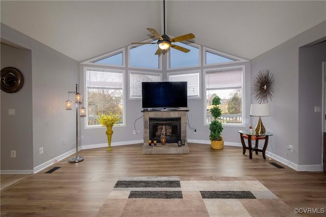 living room featuring visible vents, wood finished floors, a fireplace, lofted ceiling, and ceiling fan